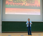 Prof. Doris Weßels steht auf einer Bühne. Über ihr wird eine Präsentation projiziert.