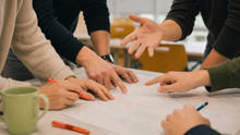 Nahaufnahme gestikulierender Hände bei einer gemeinsamen Diskussion am Tisch.